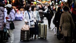 Tourists push their luggage past stalls as they visit Namdaemun Market in Seoul on March 13, 2023. (Photo by Anthony WALLACE / AFP) (Photo by ANTHONY WALLACE/AFP via Getty Images)