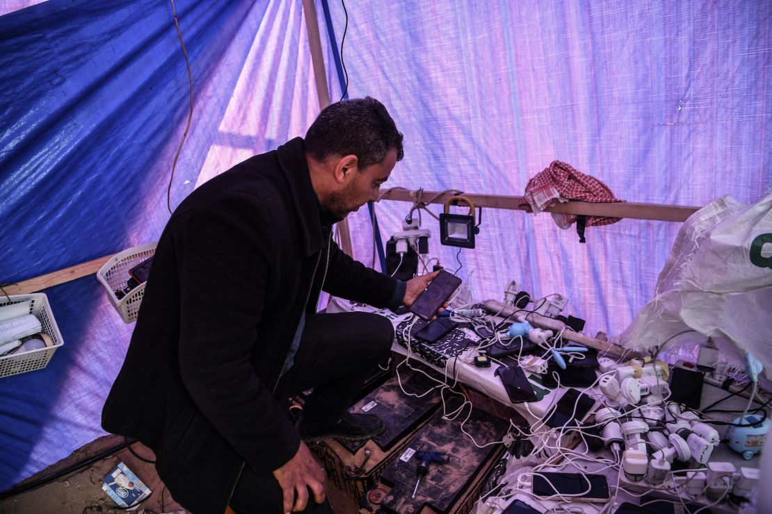 RAFAH, GAZA - JANUARY 17: Mahmoud Al-Benna produces electricity with solar panels in a makeshift tent in which Palestinians charge their phones for a minimal fee in Rafah, Gaza on January 17, 2024. (Photo by Abed Zagout/Anadolu via Getty Images)