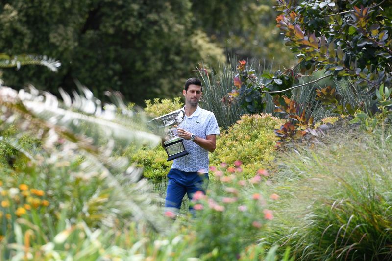 Serbia's Novak Djokovic walks in the Royal Botanical Gardens with the Norman Brookes Challenge Cup trophy during a photo shoot in Melbourne on February 3, 2020, a day after his victory against Austria's Dominic Thiem in the men's singles final of the Australian Open tennis tournament. (Photo by William WEST / AFP) / IMAGE RESTRICTED TO EDITORIAL USE - STRICTLY NO COMMERCIAL USE (Photo by WILLIAM WEST/AFP via Getty Images)