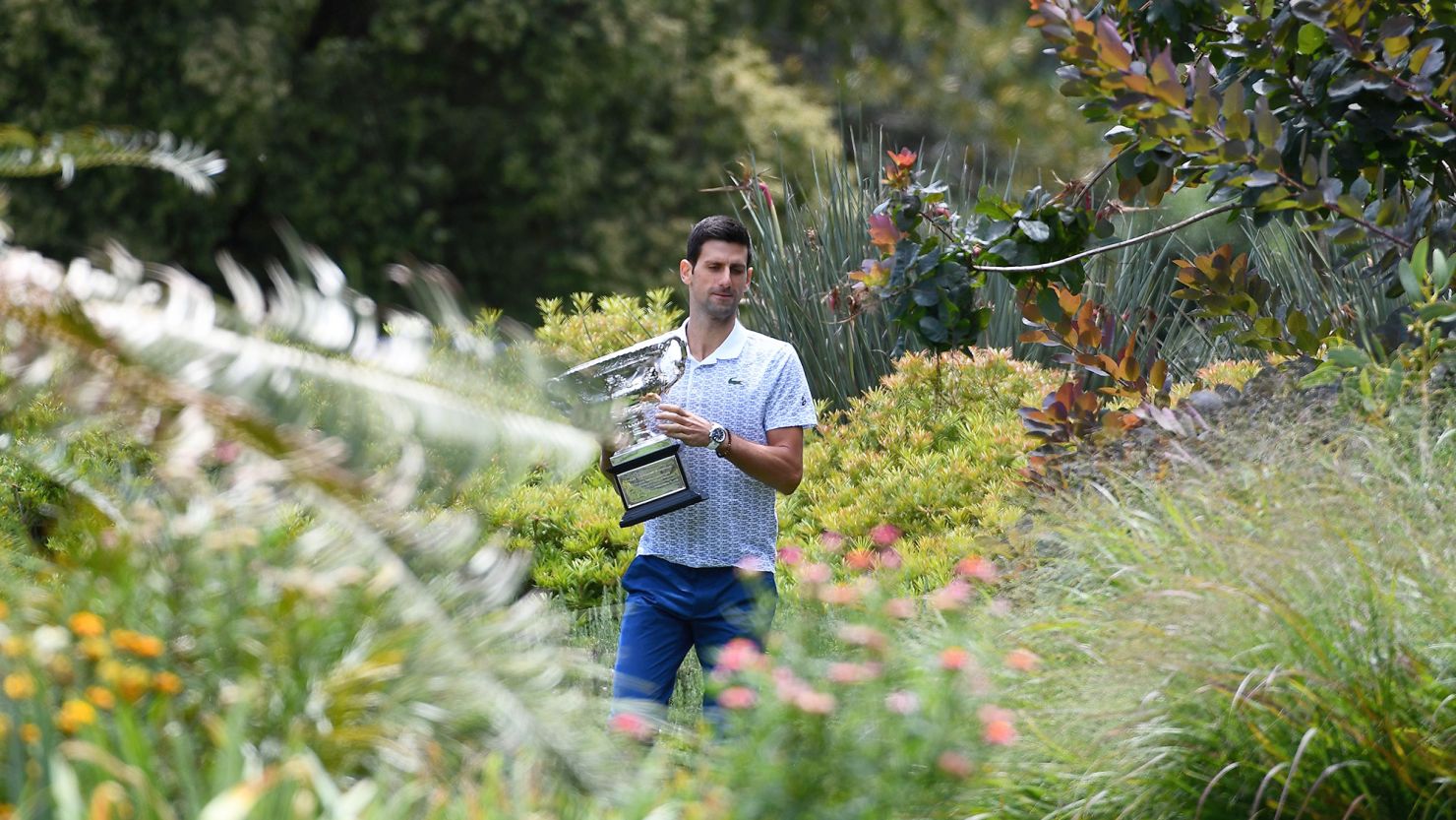 Serbia's Novak Djokovic walks in the Royal Botanical Gardens with the Norman Brookes Challenge Cup trophy during a photo shoot in Melbourne on February 3, 2020, a day after his victory against Austria's Dominic Thiem in the men's singles final of the Australian Open tennis tournament. (Photo by William WEST / AFP) / IMAGE RESTRICTED TO EDITORIAL USE - STRICTLY NO COMMERCIAL USE (Photo by WILLIAM WEST/AFP via Getty Images)