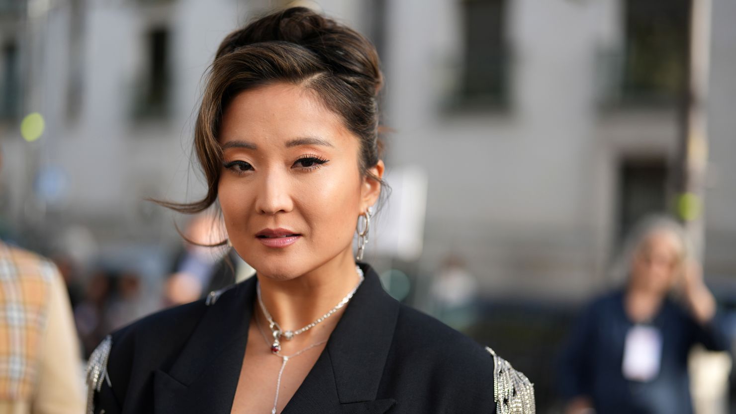 Ashley Park wears earrings, a necklace, a black oversized blazer jacket with mini chain fringe details, outside Stella McCartney, during the Womenswear Spring/Summer 2024 as part of  Paris Fashion Week on October 02, 2023 in Paris, France.