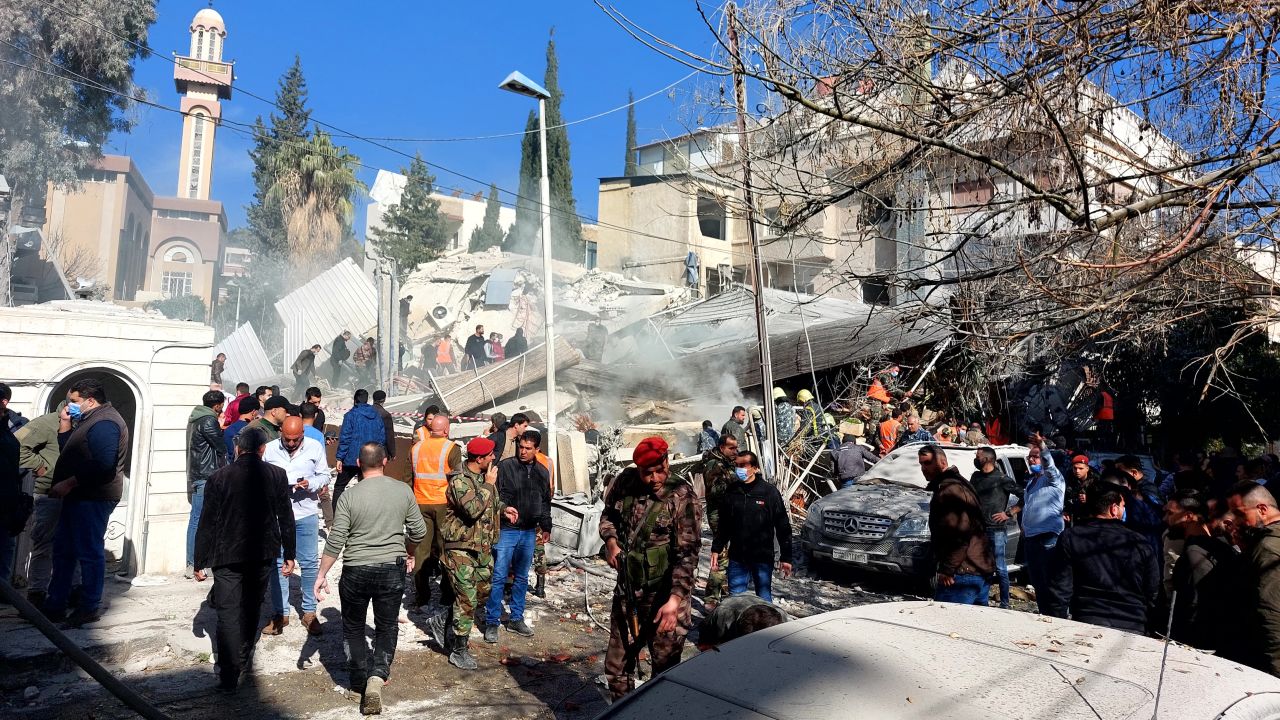TOPSHOT - People and security forces gather in front of a building destroyed in a reported Israeli strike in Damascus on January 20, 2024. An Israeli strike on Damascus killed five people in a building where "Iran-aligned leaders" were meeting on January 20, a war monitor said, as regional tensions soar over the Israel-Hamas war. (Photo by Louai Beshara / AFP) (Photo by LOUAI BESHARA/AFP via Getty Images)
