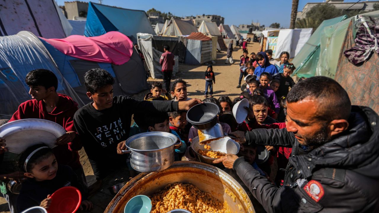 Displaced people line up to receive food cooked in large pots and distributed for free during the war near the tents in which they live on January 20, 2024 in Rafah, Gaza.