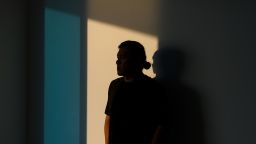 A man, completely obscured in shadow looks away - stock photo