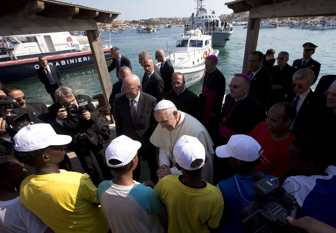 Pope Francis (C) talks with migrants at Lampedusa Island, southern Italy, July 8, 2013. Pope Francis made his first official trip outside Rome on Monday with a visit to Lampedusa, the tiny island off Sicily that has been the first port of safety for untold thousands of migrants crossing by sea from North Africa to Europe. The choice of Lampedusa is a highly symbolic one for Francis, who has placed the poor at the centre of his papacy and called on the Church to return to its mission of serving them. REUTERS/Alessandra Tarantino/Pool (ITALY - Tags: RELIGION)