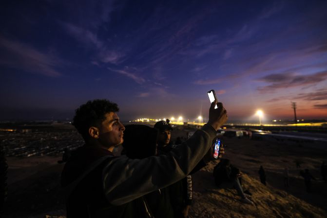 Displaced Palestinians using eSIM cards attempt to get a signal on January 19, on a hill in Rafah, on the southern Gaza border with Egypt.