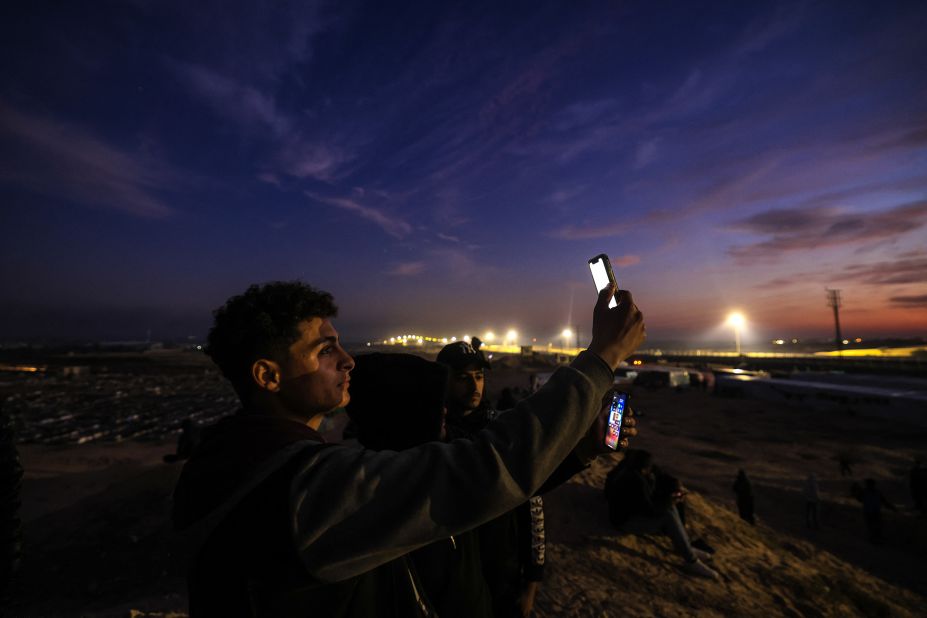 Displaced Palestinians using eSIM cards attempt to get a signal on January 19, on a hill in Rafah, on the southern Gaza border with Egypt.