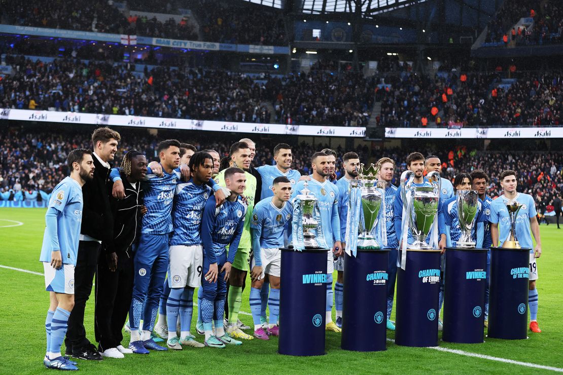 MANCHESTER, ENGLAND - DECEMBER 30: The Emirates FA Cup, English Premier League, UEFA Champions League, UEFA Super Cup and FIFA Club World Cup trophies are displayed as players of Manchester City pose for a photo prior to the Premier League match between Manchester City and Sheffield United at Etihad Stadium on December 30, 2023 in Manchester, England. (Photo by Jan Kruger/Getty Images)