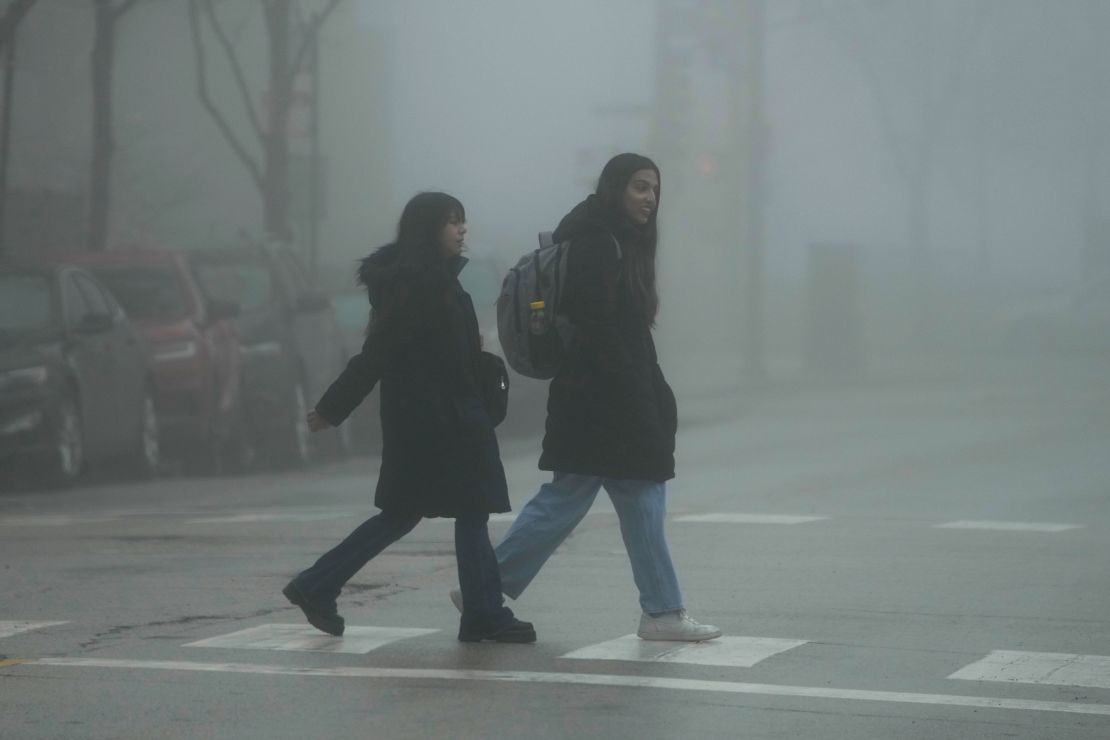Pedestrians cross a street in the fog Thursday, Jan. 25, 2024., in Chicago. Fog and occasional drizzle builds to late-day rain commencing near or during the evening commute period.