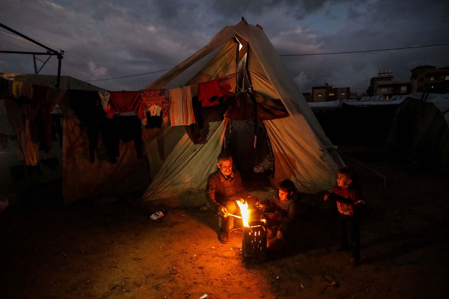 Displaced Palestinians keep warm by a fire near their tent in Rafah, Gaza, on Tuesday, January 23. According to the UN's Office for the Coordination of Humanitarian Affairs, at least 1.7 million people in Gaza <a href="index.php?page=&url=https%3A%2F%2Fwww.cnn.com%2F2024%2F01%2F25%2Fmiddleeast%2Ftorrential-rain-gaza-israel-khan-younis-offensive-intl%2Findex.html" target="_blank">have been internally displaced</a> since Israel launched its offensive in the territory, aiming to eliminate the Hamas militant group.