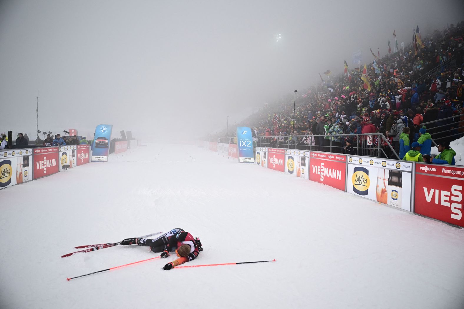 German biathlete Roman Rees falls to the ground in exhaustion after crossing the finish line at a World Cup event in Antholz-Anterselva, Italy, on Thursday, January 18. He finished in 10th place.
