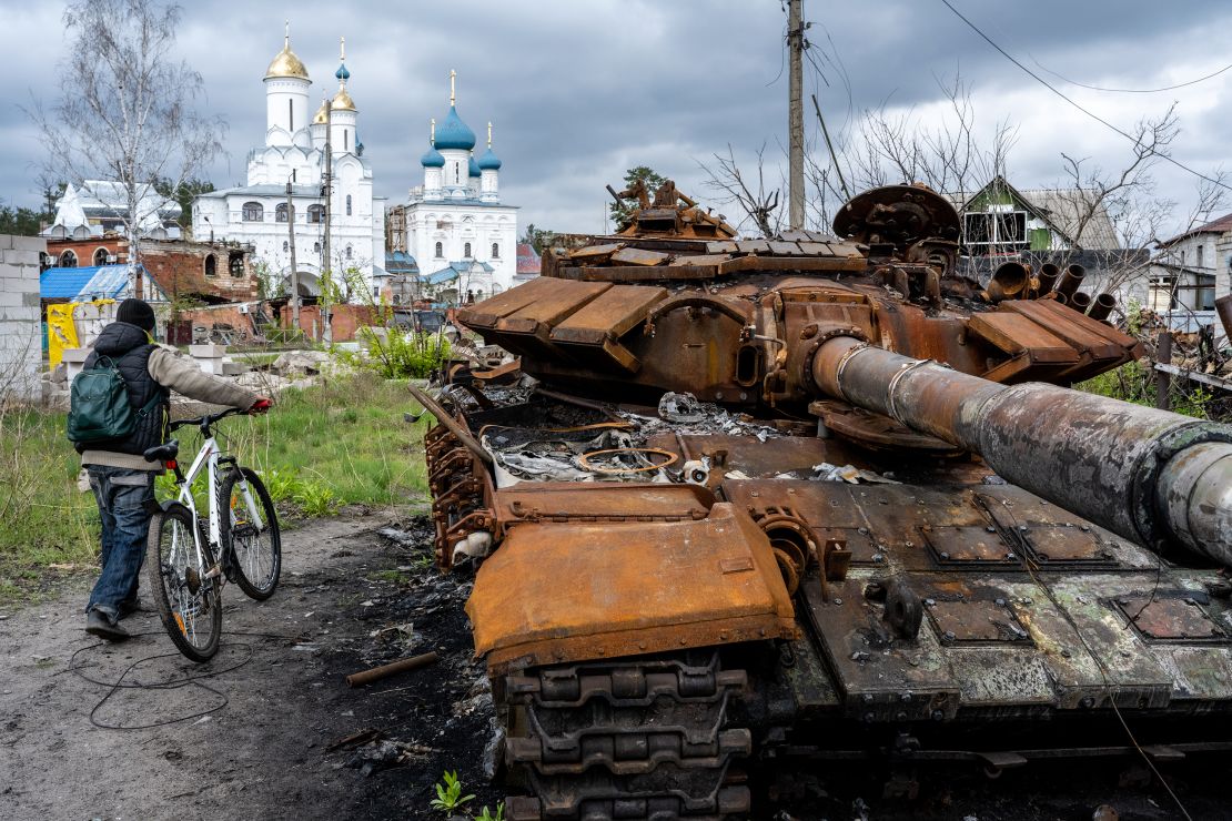 A cyclist passes a destroyed Russian tank that lies near the Cathedral of Saints Vera, Nadeshda and Liubov, an Orthodox Church loyal to the Moscow Patriarchate, as Ukrainians in a monastery town once occupied by Russian troops strive to restore normal life and unify their community in Sviatohirsk, Ukraine, on April 22, 2023. Three months of Russian occupation left the city severely damaged and with just 550 members of its pre-war population of 4,000-plus, but Ukrainian officials say they are working to restore services and trust to overcome deep divisions caused by the war and by residual pro-Russia sentiment.
