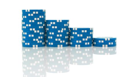 Four stacks of blue poker chips on a pure white background with reflection.