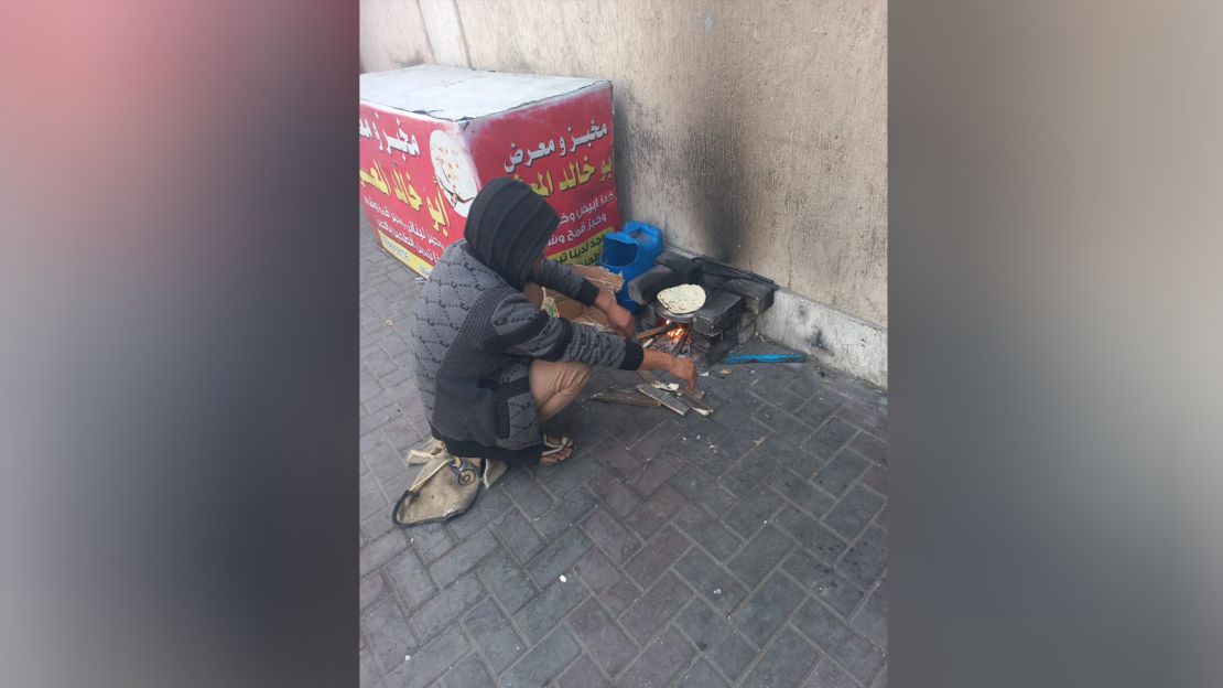 A displaced man makes bread next to a tent he set up on a sidewalk in Rafah, in southern Gaza, on January 22, 2024.
