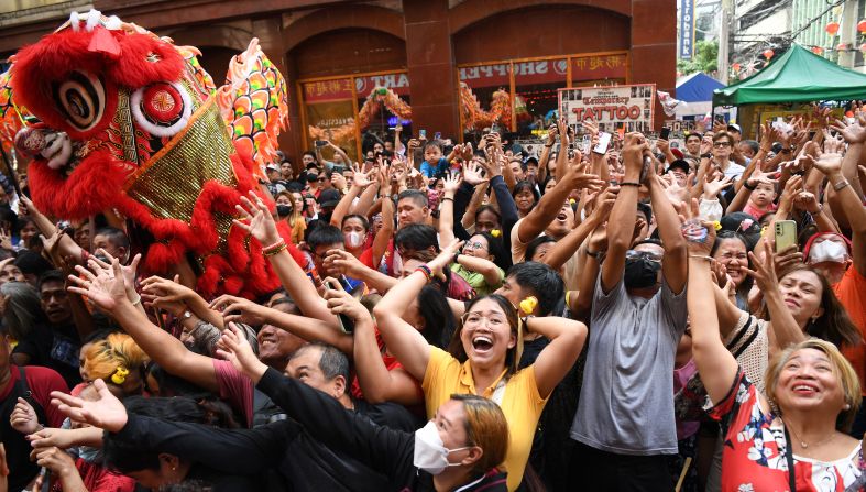 People try to catch red envelopes next to a lion figurine during celebrations in Chinatown in Manila, Philippines. on February 10.