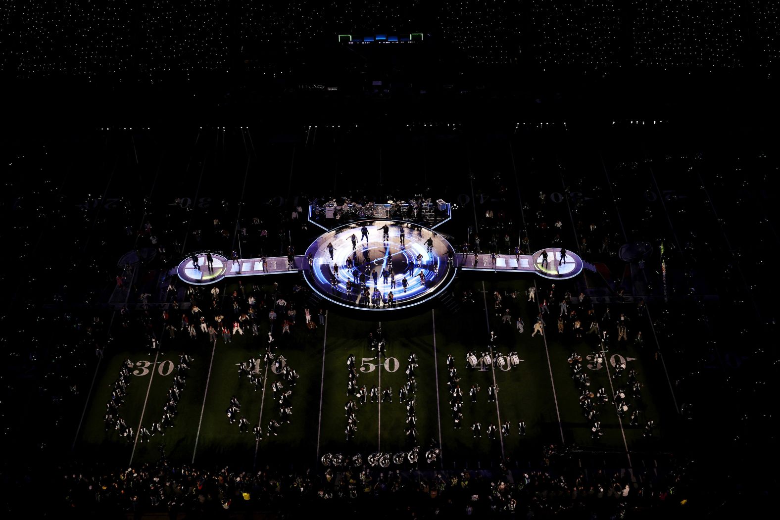 Members of a marching band spell out "Usher" on the field.