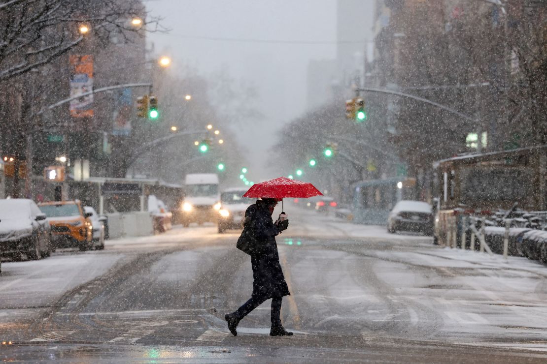 Un pedone tiene in mano un ombrello mentre cade la neve durante una tempesta invernale a Nor'Easter a New York, negli Stati Uniti, il 13 febbraio 2024.  REUTERS/Andrea Kelly