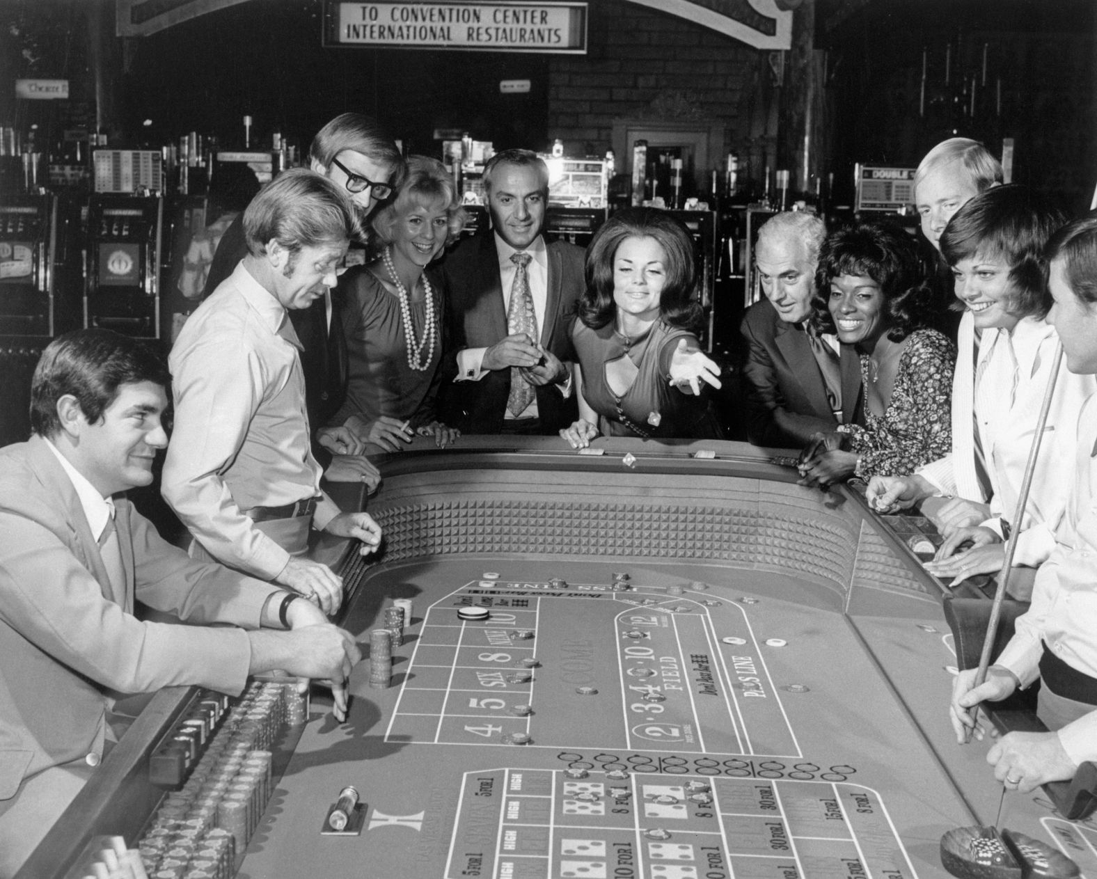 A woman throws dice at a craps table in the 1960s.