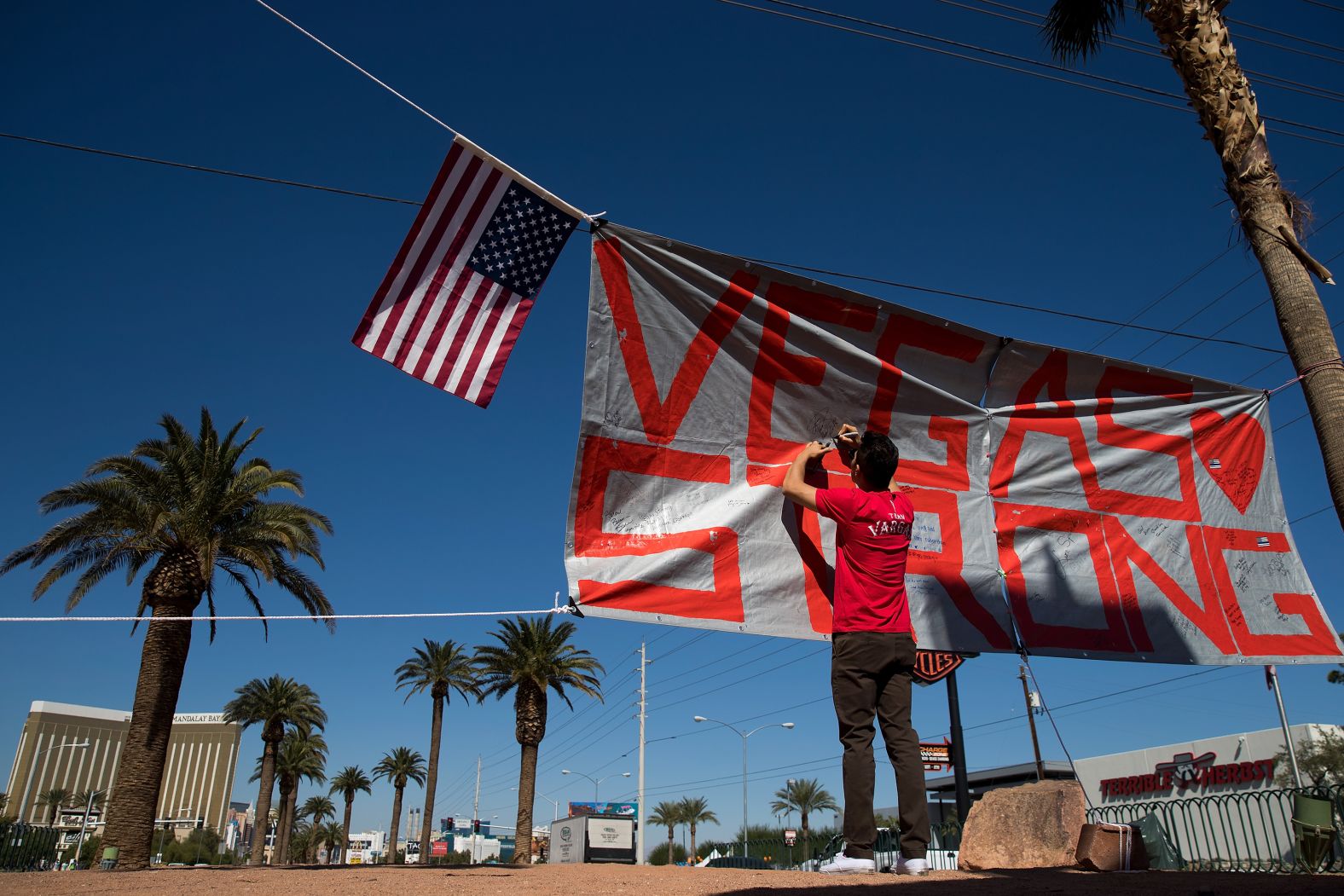 A man writes a note on a Vegas Strong banner in 2017. Days earlier, dozens of people were killed and hundreds were injured when a gunman opened fire at a country music festival on the Las Vegas Strip. It is the deadliest mass shooting in US history.