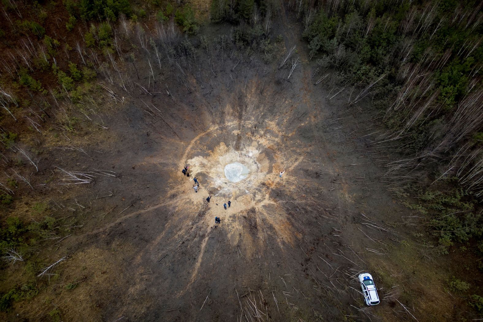 People stand around a crater created by a Russian missile strike in the Ukrainian village of Buda-Babynetska on Thursday, February 15.
