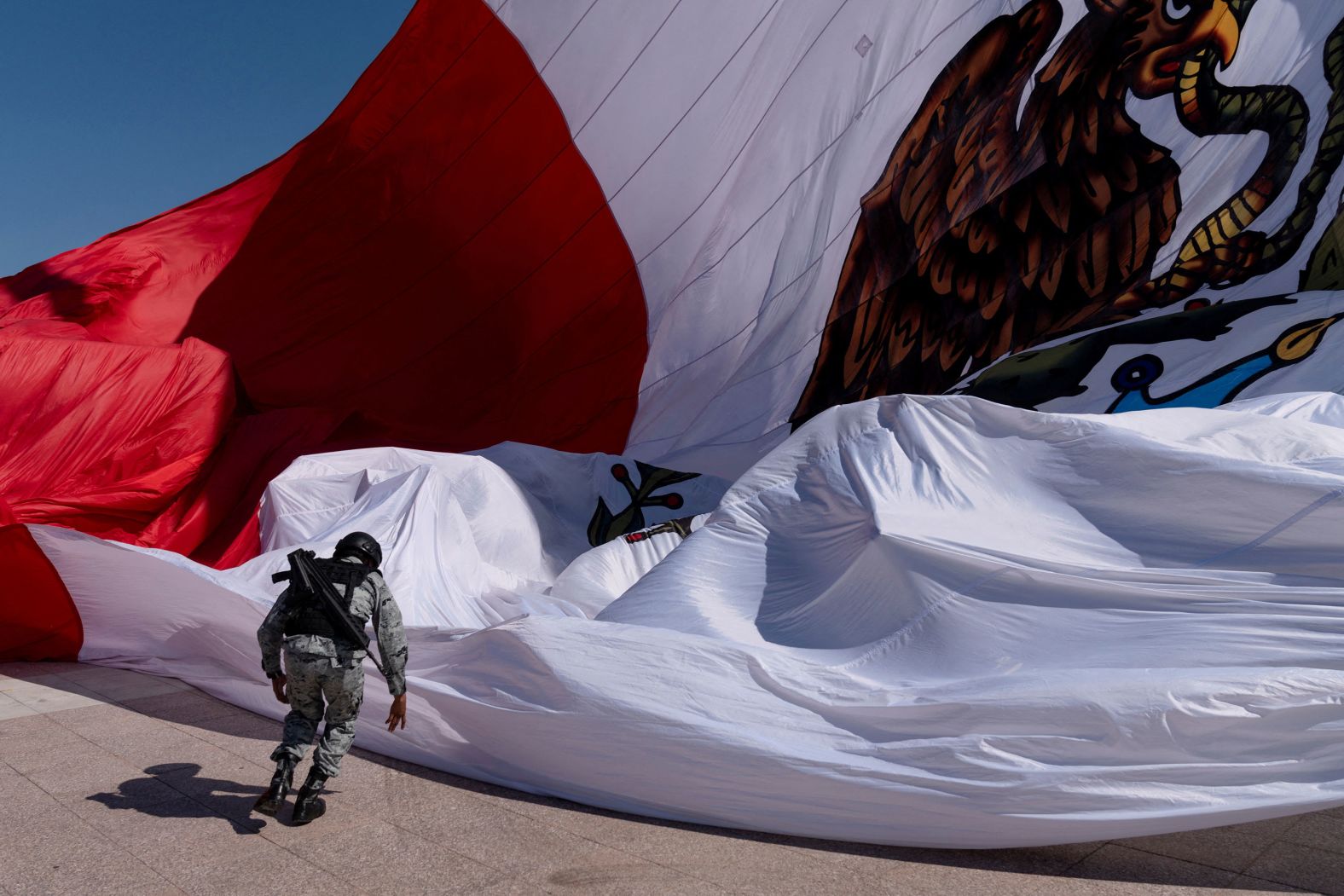 A member of the Mexican National Guard races to secure a giant national flag as it is unfurled during Flag Day celebrations in Piedras Negras, Mexico, on Saturday, February 24.