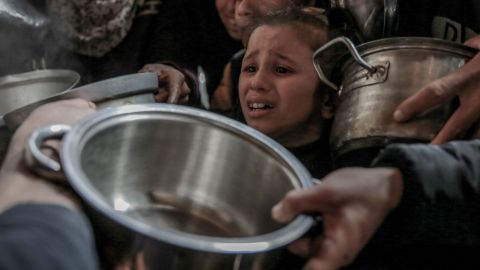 GAZA CITY, GAZA - FEBRUARY 26: A child is seen crying amid others with empty containers, pans as they all wait to receive hot food distributed by charitables and charity organization in Gaza City, Gaza on February 26, 2024. Palestinians are unable to obtain basic food supplies due to the embargo imposed by Israeli forces. (Photo by Omar Qattaa/Anadolu via Getty Images)
