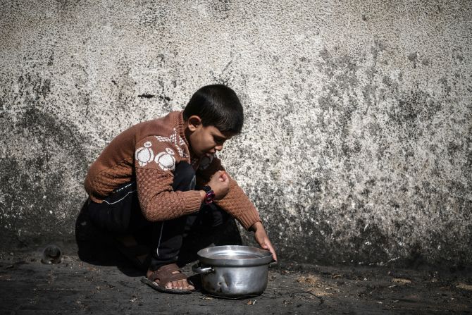 A Palestinian child crouches by her food container after a distribution in Rafah on January 25.
