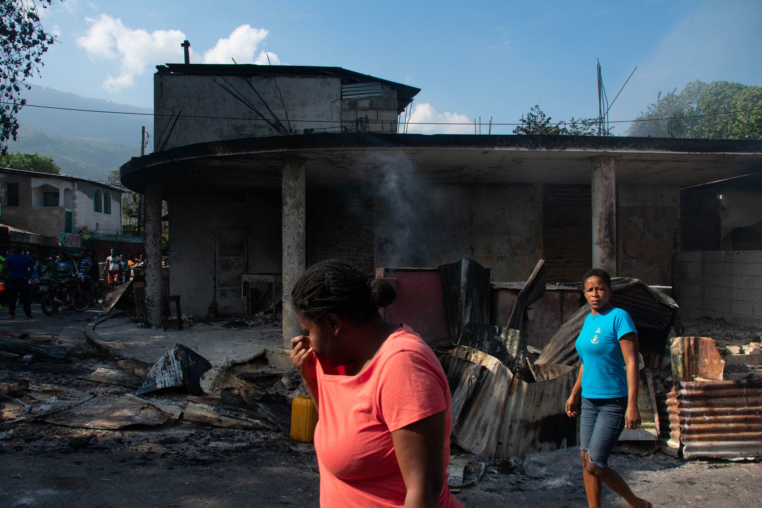 A woman cries as she walks near her husband's shop that was set on fire by armed gang members in Port-au-Prince, Haiti, on Thursday, March 7.