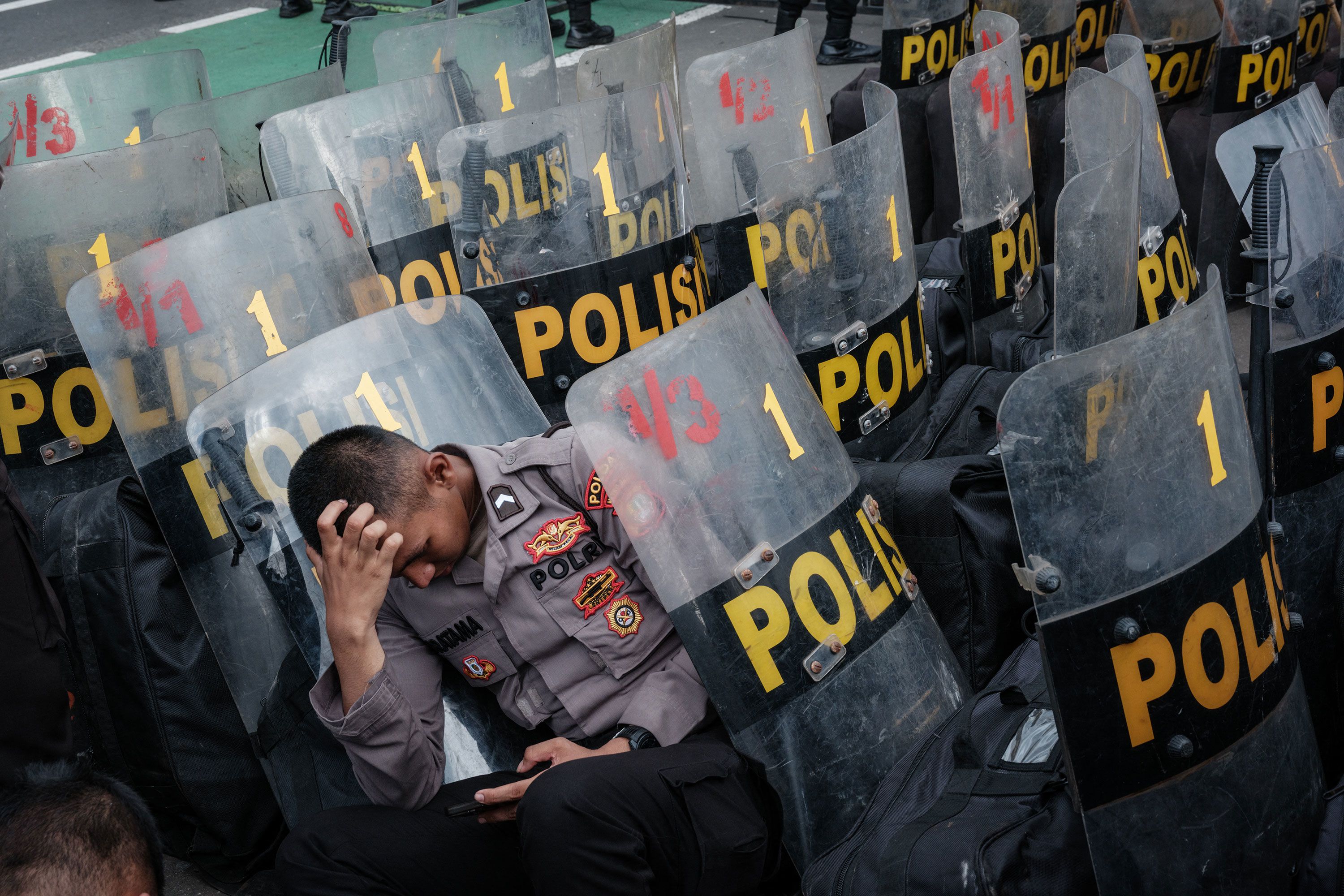 A police officer rests among shields in Jakarta, Indonesia, during a demonstration demanding the impeachment of Indonesian President Joko Widodo.