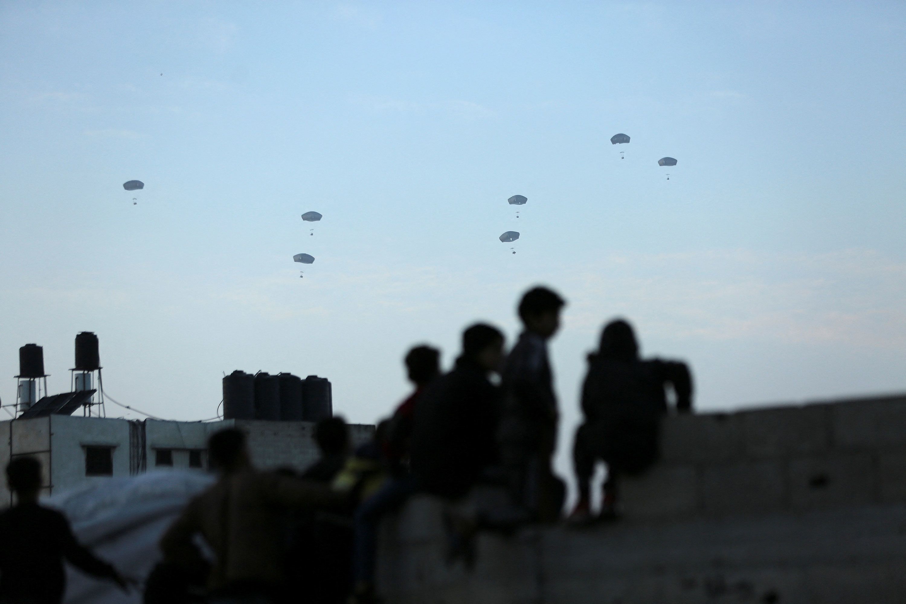 People in Gaza City watch as the US military carries out its first aid drop over Gaza on Saturday, March 2.