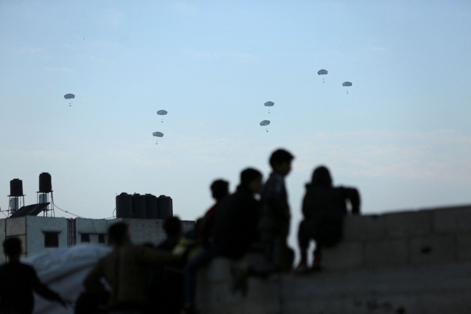 People in Gaza City watch as the US military carries out its first aid drop over Gaza on Saturday, March 2. <a href="index.php?page=&url=https%3A%2F%2Fwww.cnn.com%2F2024%2F03%2F02%2Fpolitics%2Fus-airdrops-aid-gaza%2Findex.html" target="_blank">The combined operation</a> by the US Air Force and the Royal Jordanian Air Force saw US aircraft dropping 38,000 meals along the Gaza coastline, CENTCOM said in a statement.
