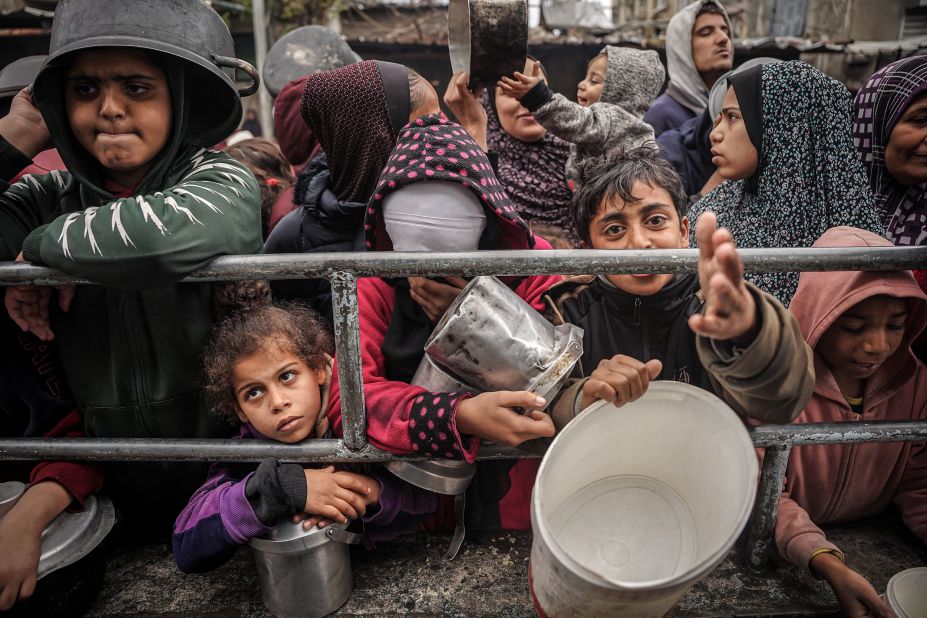 Palestinians wait to receive food at a refugee camp in Rafah on January 27.