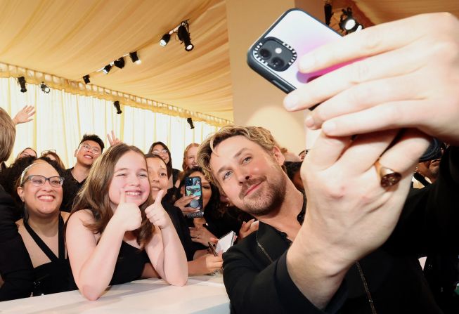 Gosling poses with fans while walking on the red carpet.