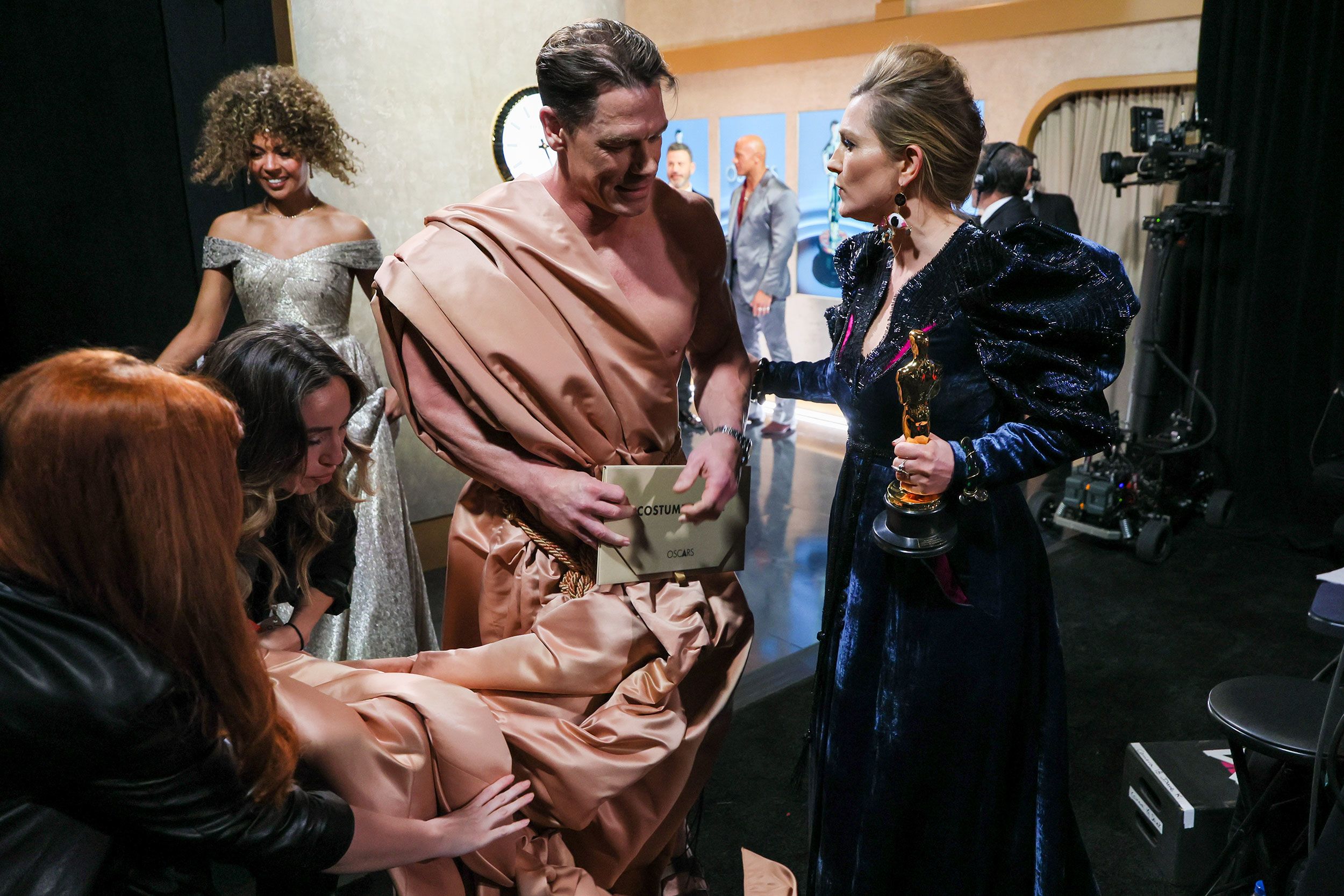 John Cena and Holly Waddington talk backstage after Cena presented Waddington with the Oscar for best costume design ("Poor Things").