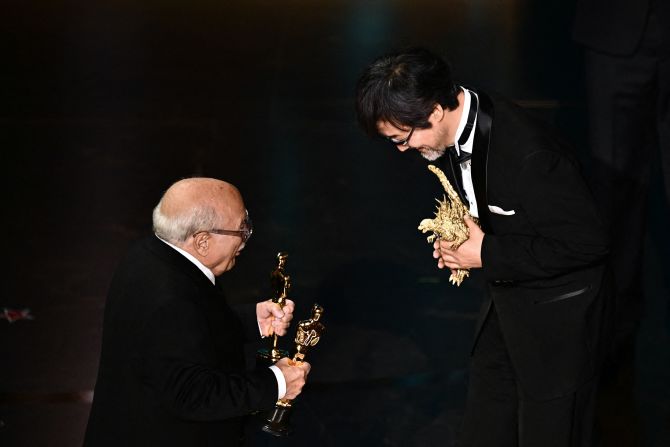 Danny DeVito, left, presents the Oscar for best visual effects to Takashi Yamazaki and "Godzilla Minus One."