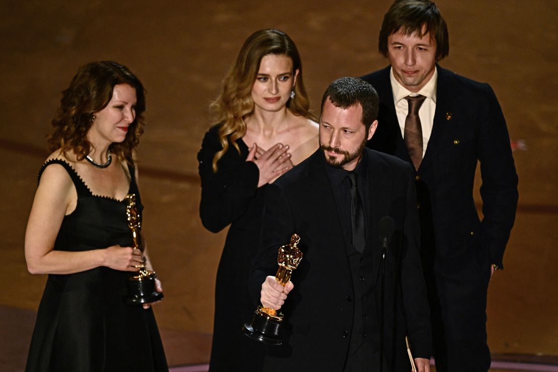 TOPSHOT - Ukrainian filmmaker Mstyslav Chernov (C), flanked by (from L) Raney Aronson-Rath, Vasilisa Stepanenko and Evgeniy Maloletka, accepts the award for Best Documentary Feature Film for 