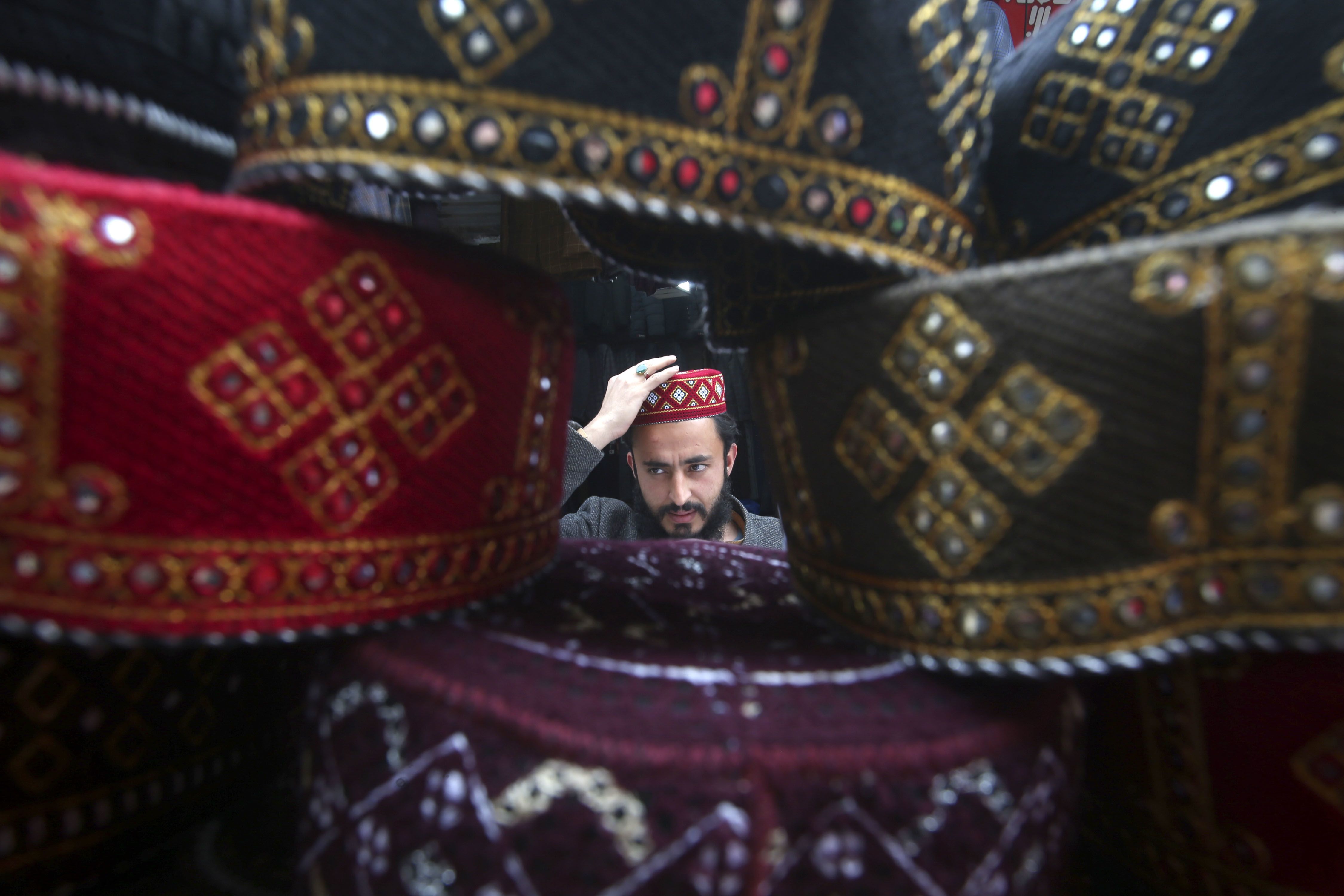 A man tries on a traditional cap which will be used while praying during Ramadan, at a stall in Peshawar, Pakistan.