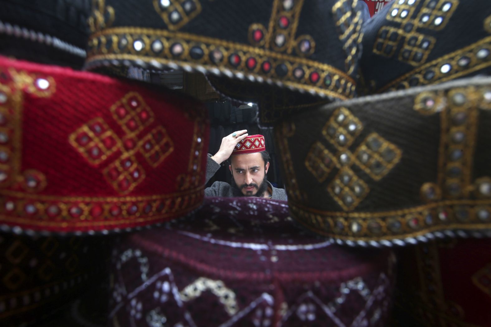 A man tries on a traditional cap which will be used while praying during Ramadan, at a stall in Peshawar, Pakistan. 