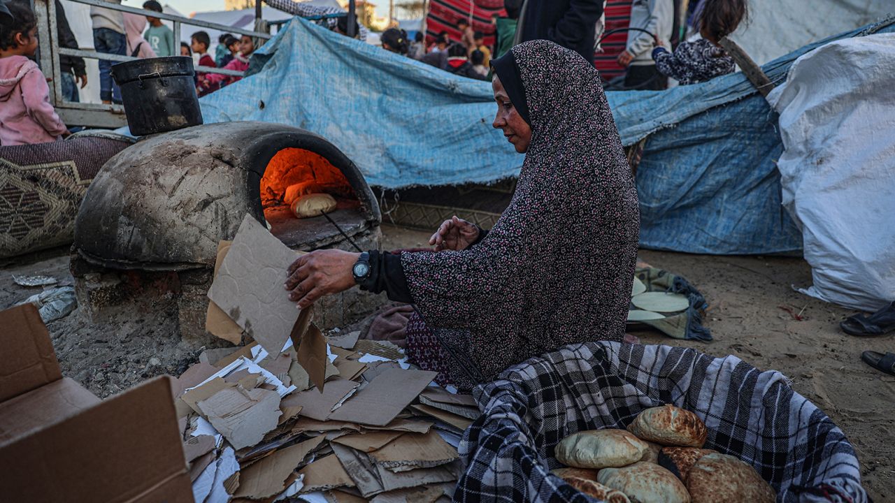 A displaced Palestinian woman bakes bread before an iftar meal, the breaking of fast, on the first day of the Muslim holy fasting month of Ramadan, in Rafah in the southern Gaza Strip on March 11, 2024, amid ongoing battles between Israel and the militant group Hamas. 
