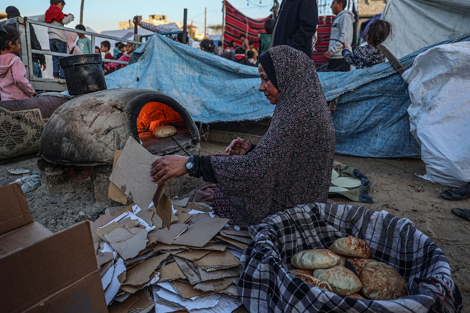 A displaced Palestinian woman bakes bread before an iftar meal in Rafah, Gaza.