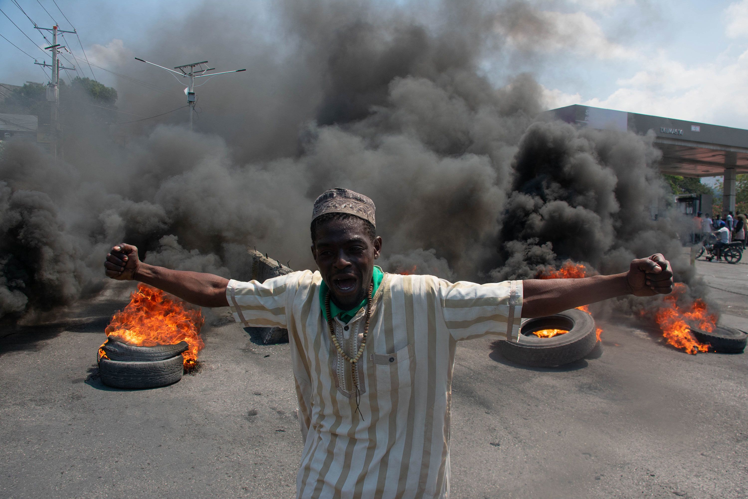 A protester reacts while tires burn in a street in Port-au-Prince, Haiti, on Tuesday, March 12.