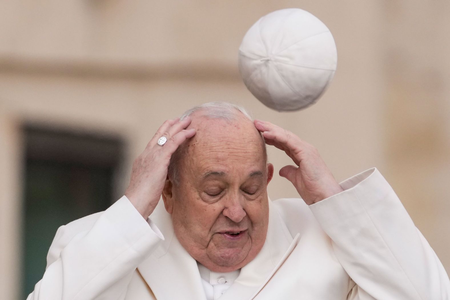Pope Francis tries to catch his cap in St. Peter's Square as the wind blows it away at the Vatican on Wednesday, March 13.