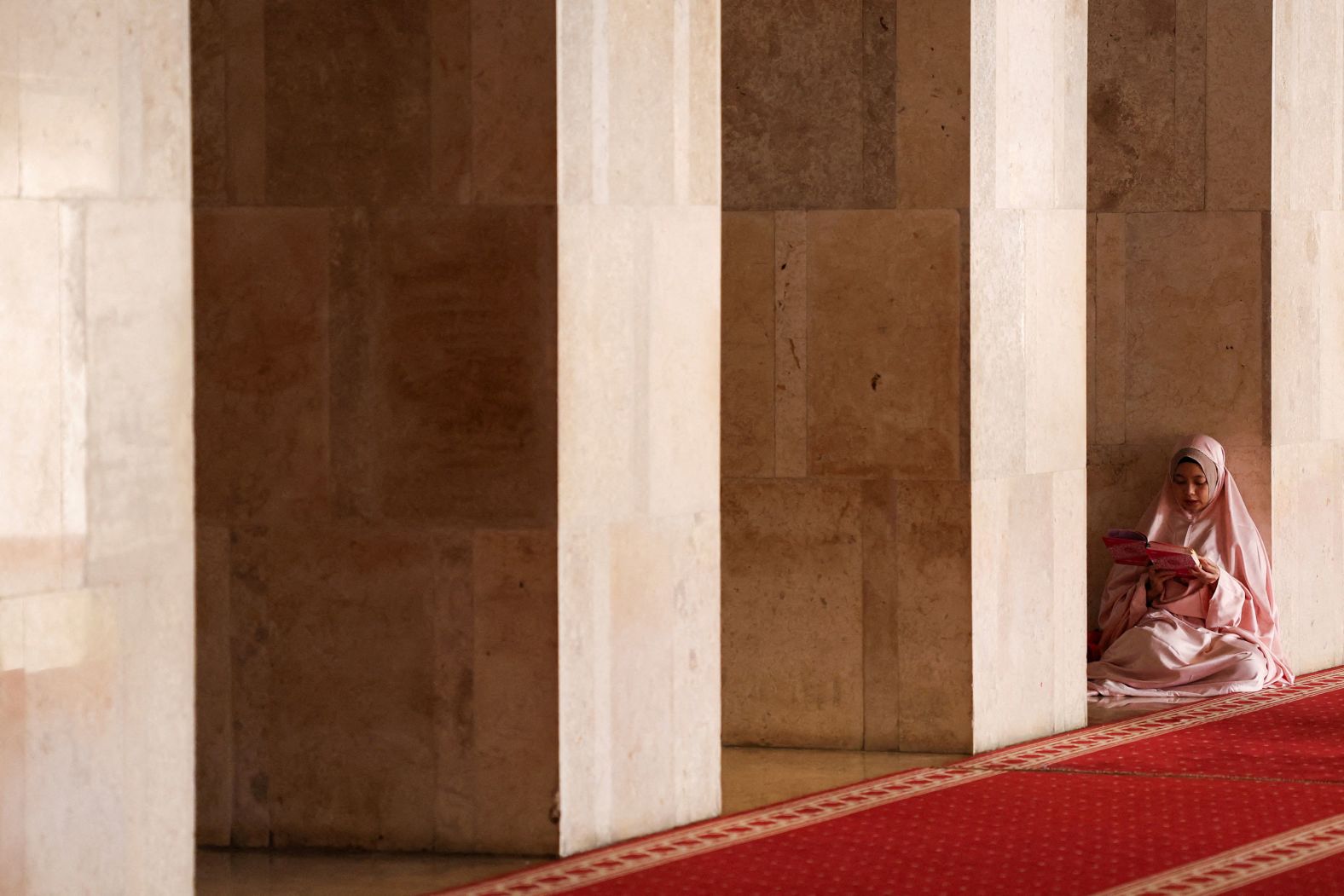 A woman reads the Quran at the Istiqlal Mosque in Jakarta, Indonesia, while waiting to break her Ramadan fast on Tuesday, March 12.