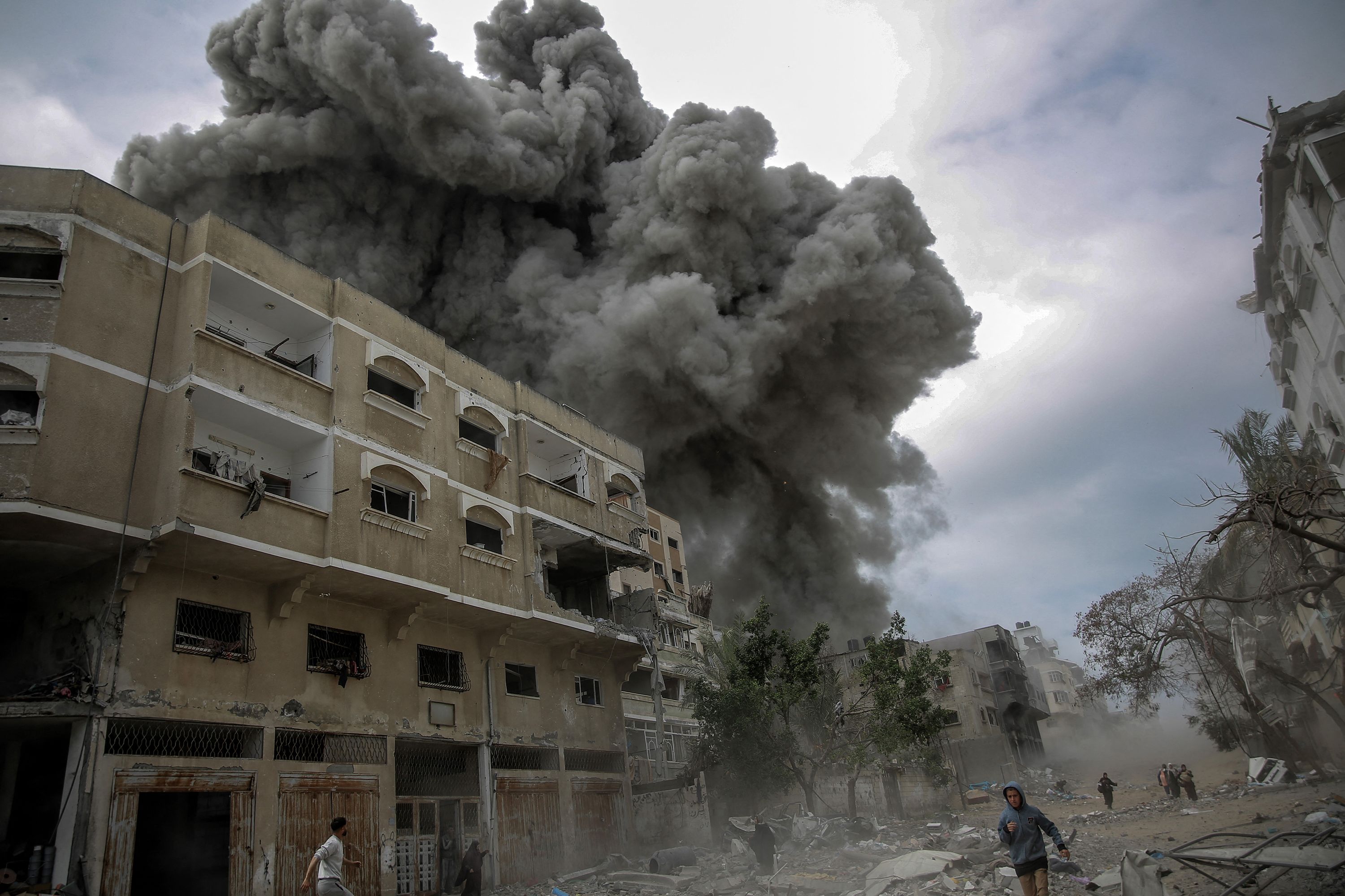 Palestinians rush for cover as smoke billows after an Israeli bombardment in central Gaza City on Monday, March 18.