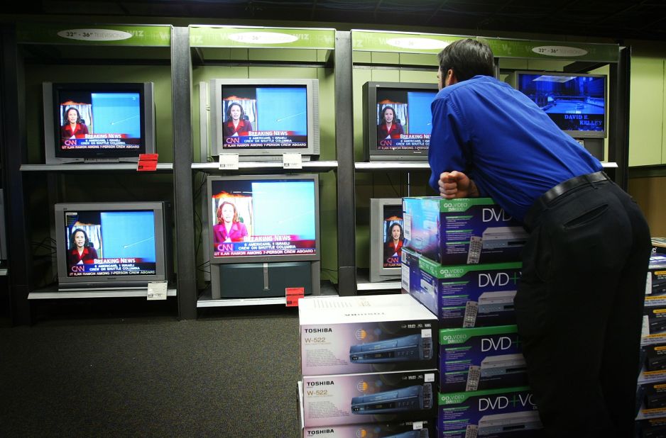 A store employee in New York pauses to watch a breaking news broadcast about Space Shuttle Columbia minutes before its scheduled landing on February 1, 2003.