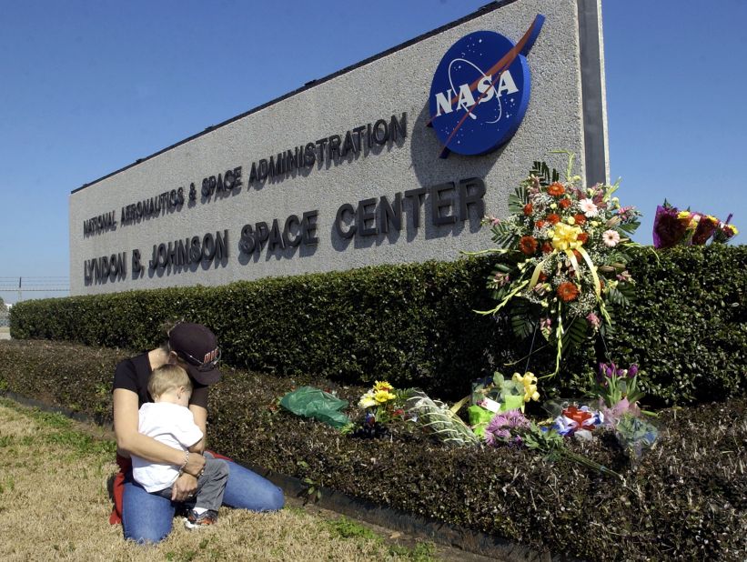 Kathryn O'Neill of Laguna Hills, California, and her son Zachary kneel by the entrance sign of Johnson Space Center in Houston on February 1, 2003. A makeshift memorial for the STS-107 crew had been set up there.