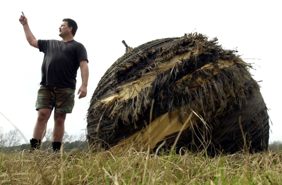 Tommy Peltier of Houston stands next to debris from Space Shuttle Columbia that fell near San Augustine, Texas, on February 2, 2003.