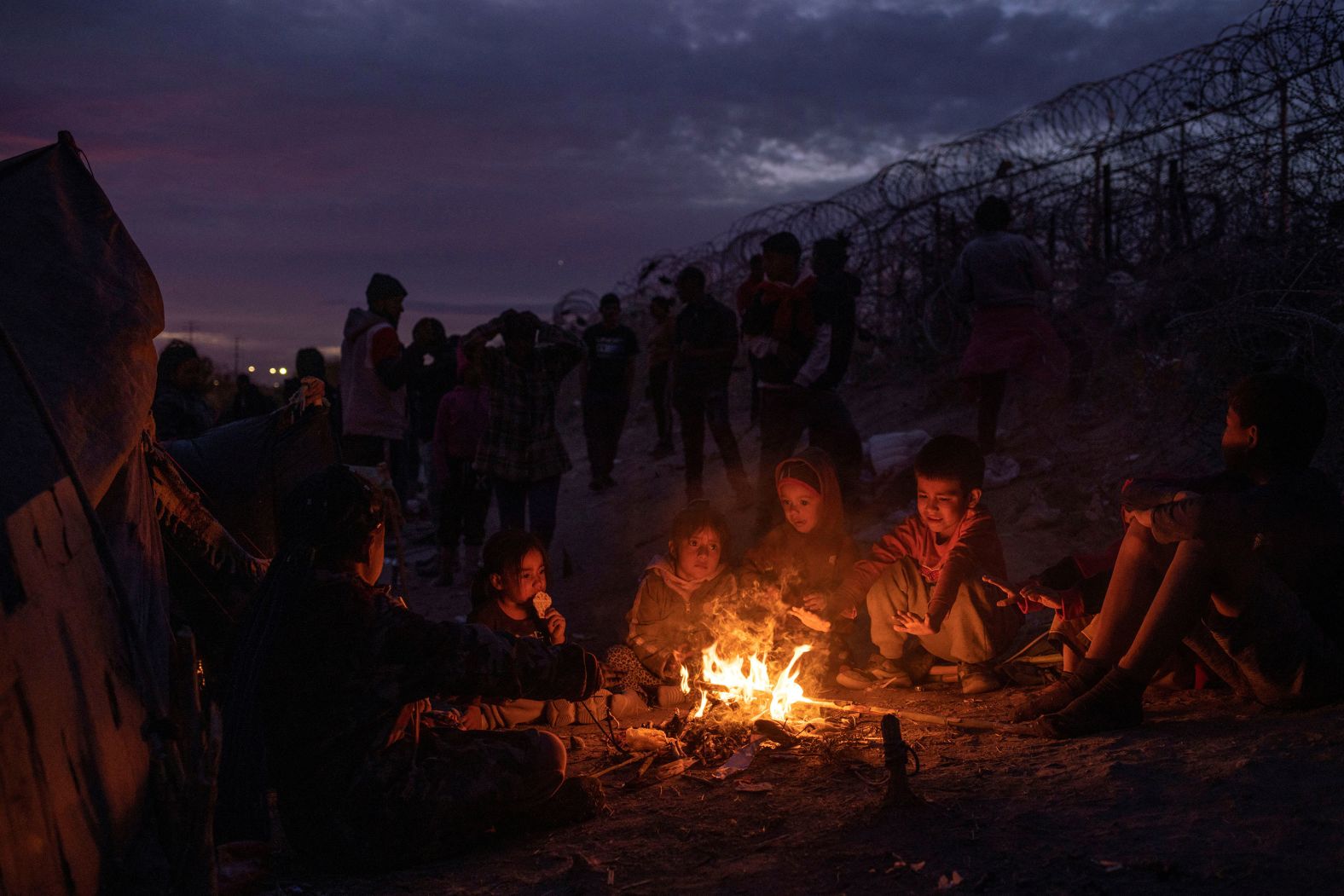 Migrant children sit around a fire along the bank of the Rio Grande river on Saturday, March 23, as they wait with their families to surrender to immigration authorities in Texas.
