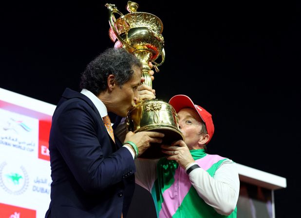 Trainer Bhupat Seemar and jockey Tadhg O'Shea kiss the trophy after winning the Dubai World Cup in 2024.