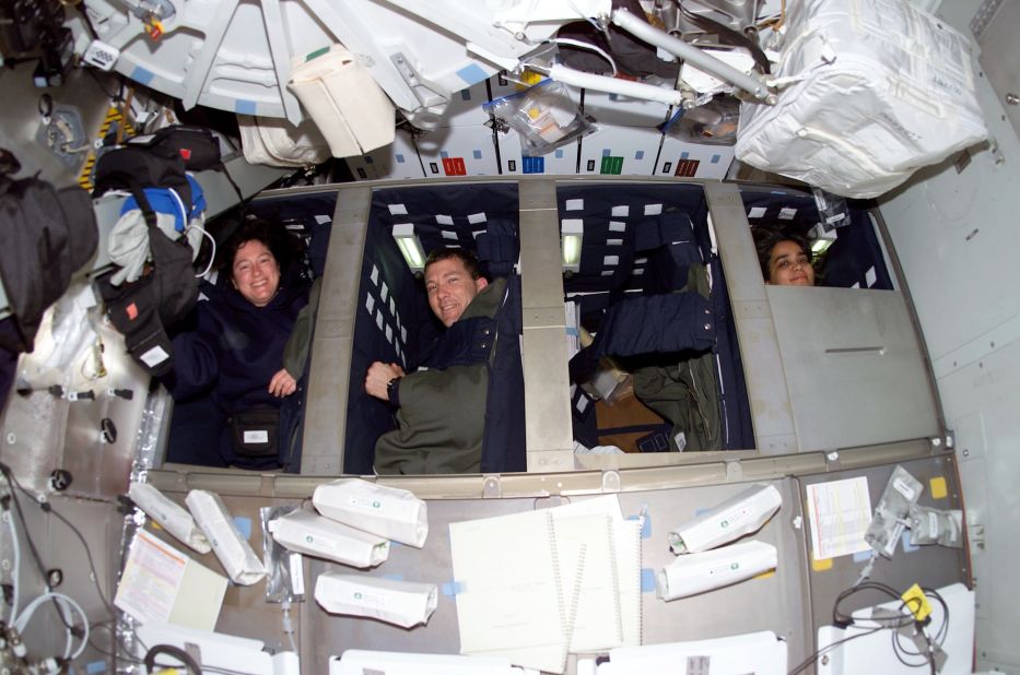 Some of the STS-107 crew are pictured prior to their sleep shift in bunk beds on the middeck of Space Shuttle Columbia on January 20, 2003. From left are Clark, Husband and Chawla. Along with Ramon, out of frame, they were members of the Red Team; Anderson, Brown, and McCool were on the Blue Team. The teams worked opposite shifts in order to perform continuous research for 16 days.